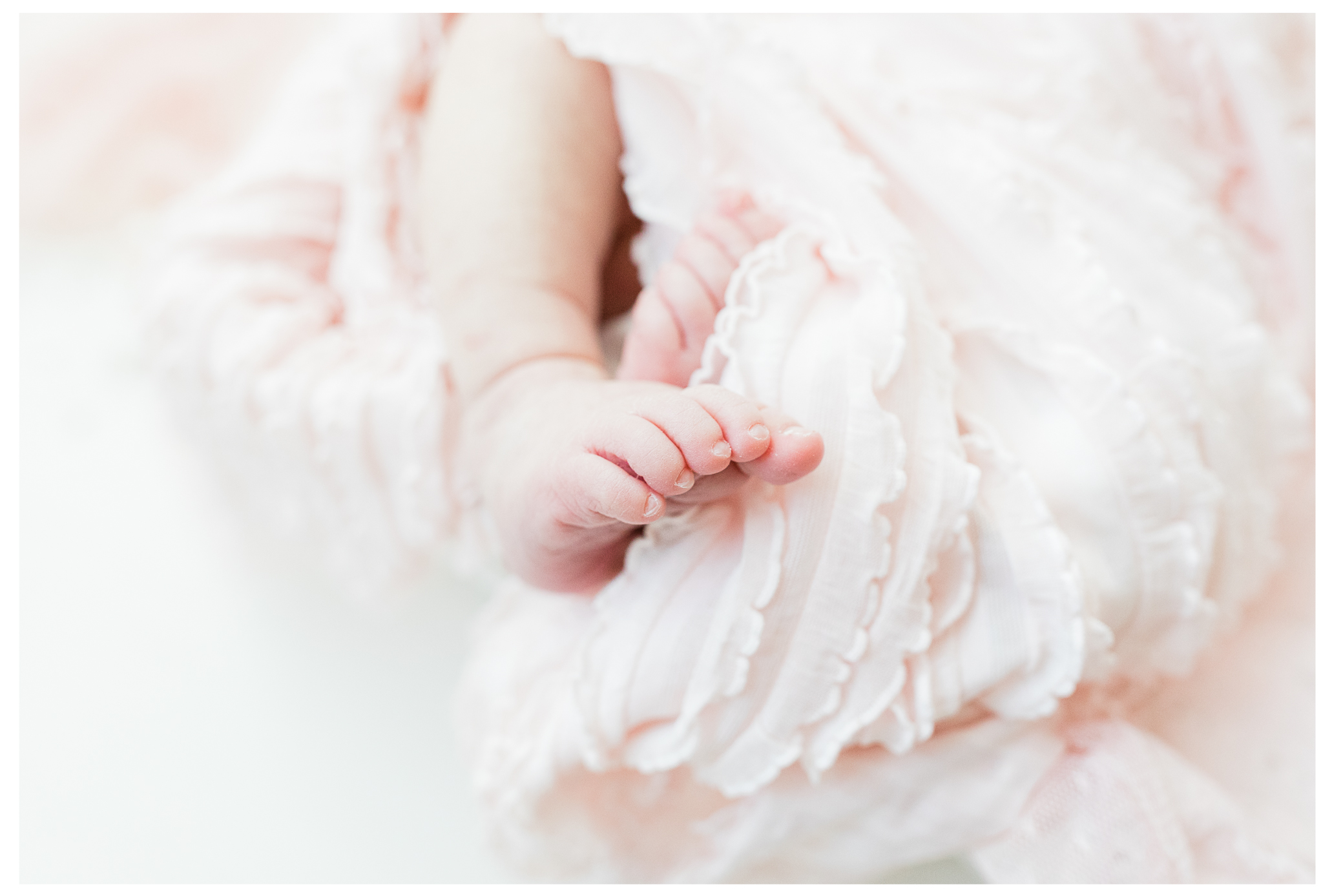 A close image of newborn toes next to a pink blanket