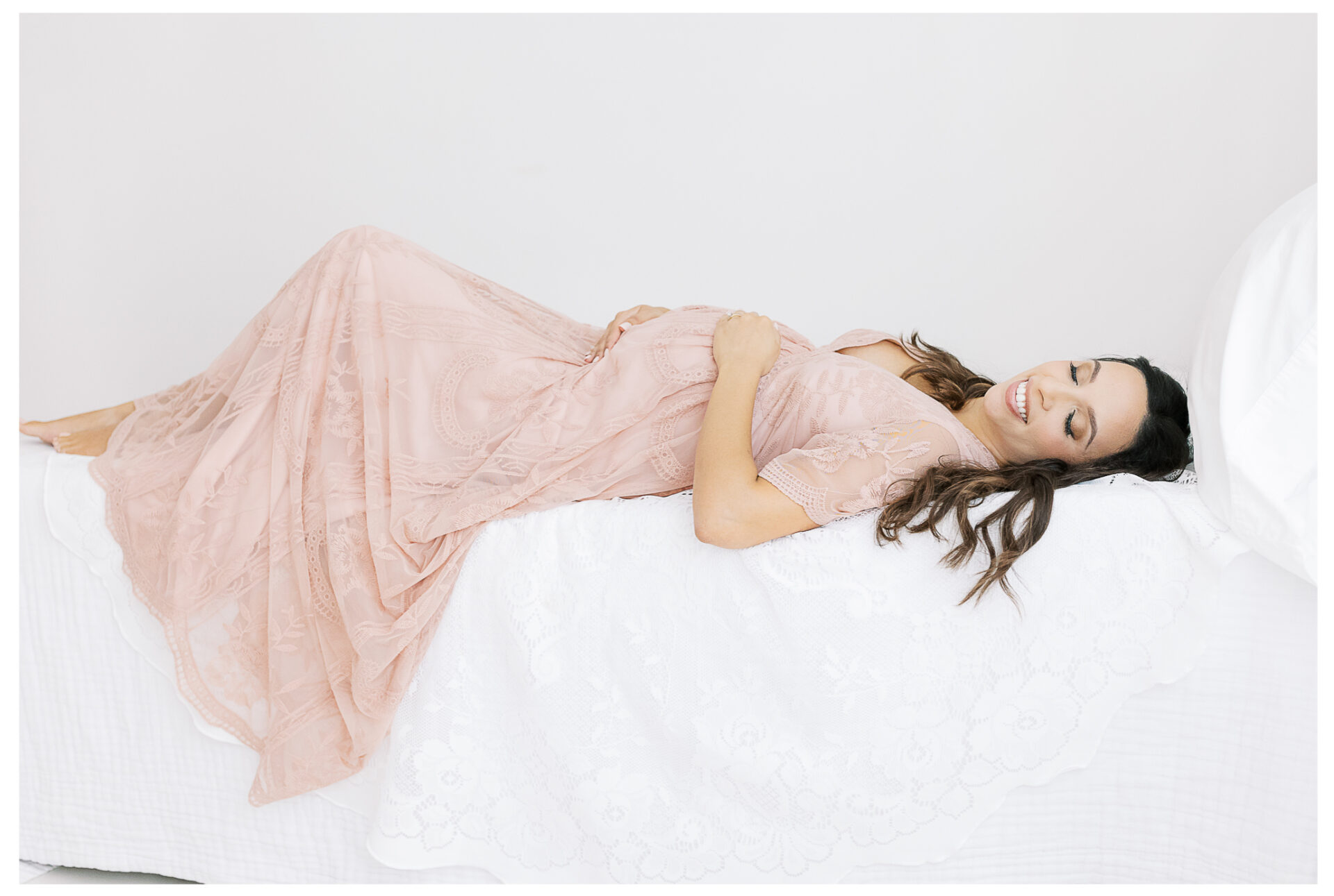 Winter Freire Photography | Natural Light Studio Maternity Session in Dayton, OH | Mama-to-be laying down on a white bed