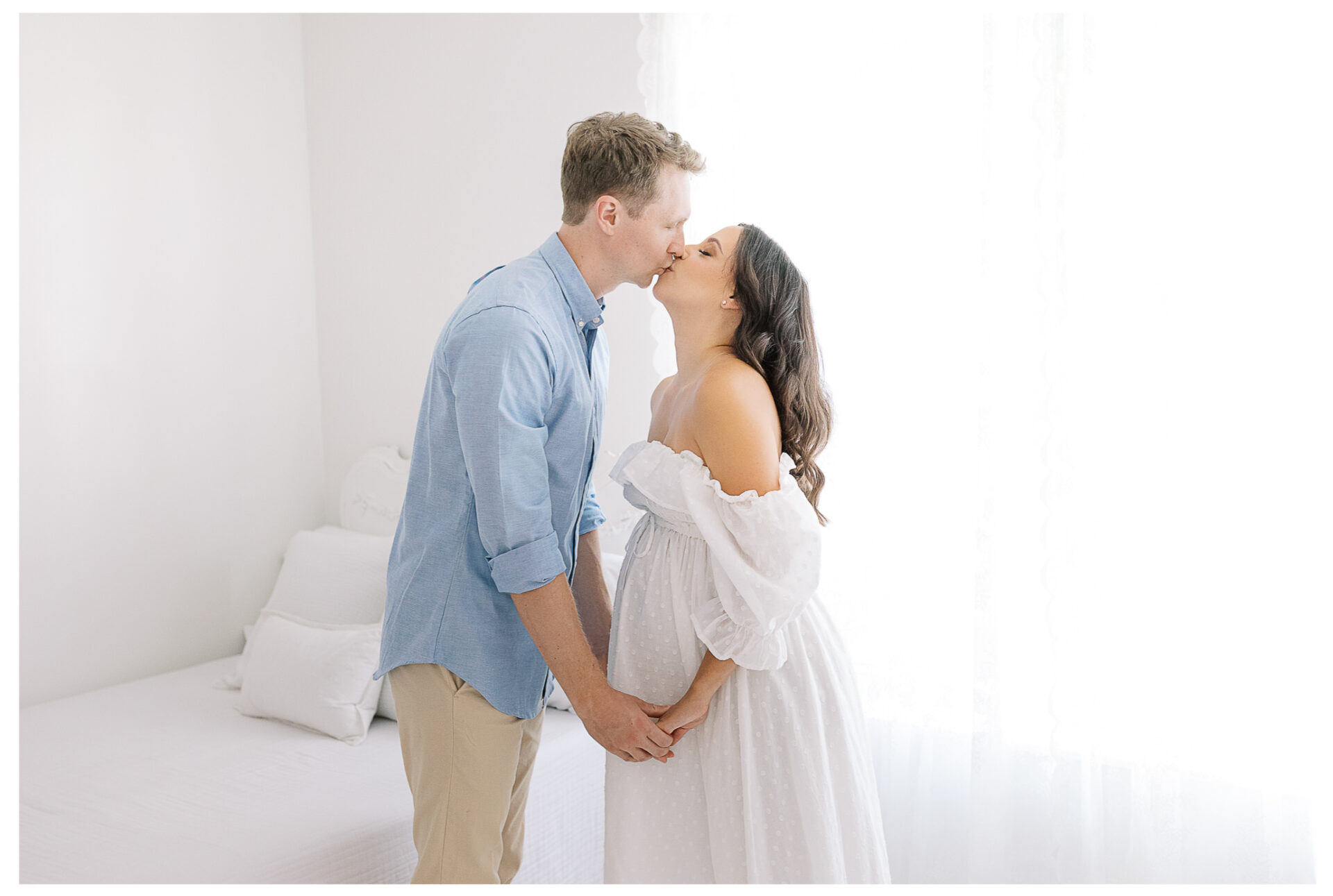 Winter Freire Photography | Natural Light Studio Maternity Session in Dayton, OH | Mama-to-be and husband kissing with their hands on the baby bump