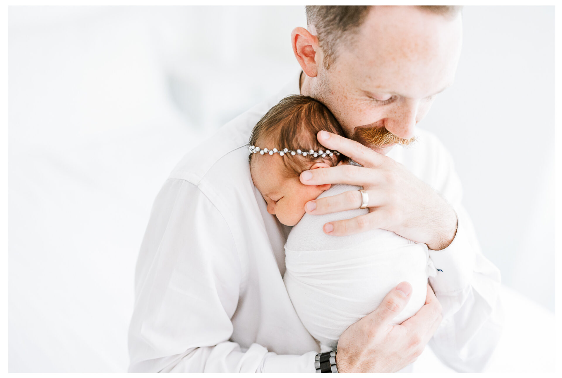 Winter Freire Photography | Dayton, Ohio Newborn Session | Dad sitting on a bed while holding his newborn baby girl
