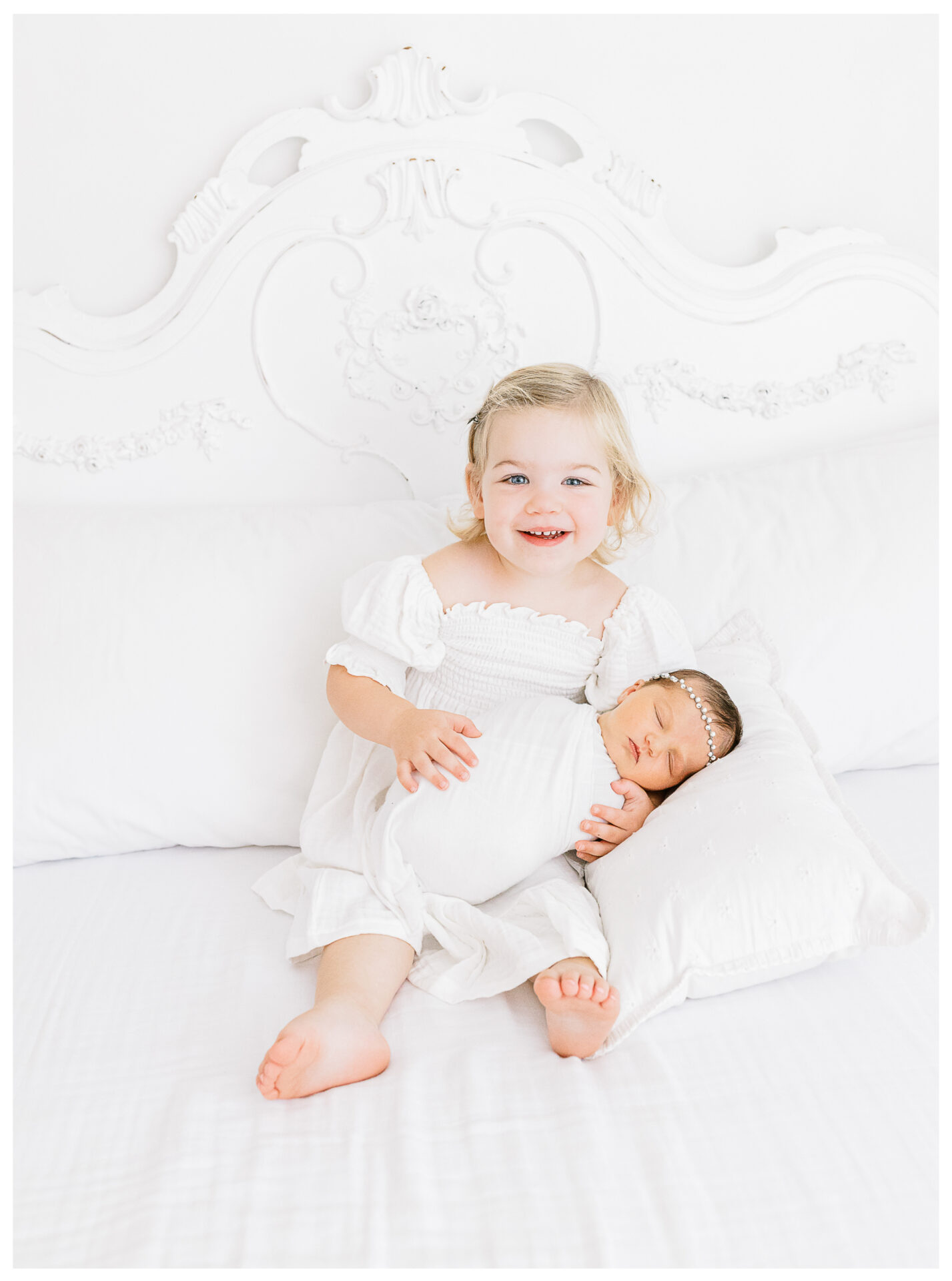 Winter Freire Photography | Dayton, Ohio Newborn Session | Daughter holding her newborn sister while sitting on a bed