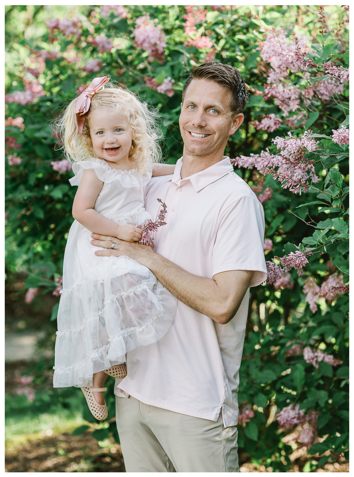 A father holding his youngest daughter while both smile broadly.
