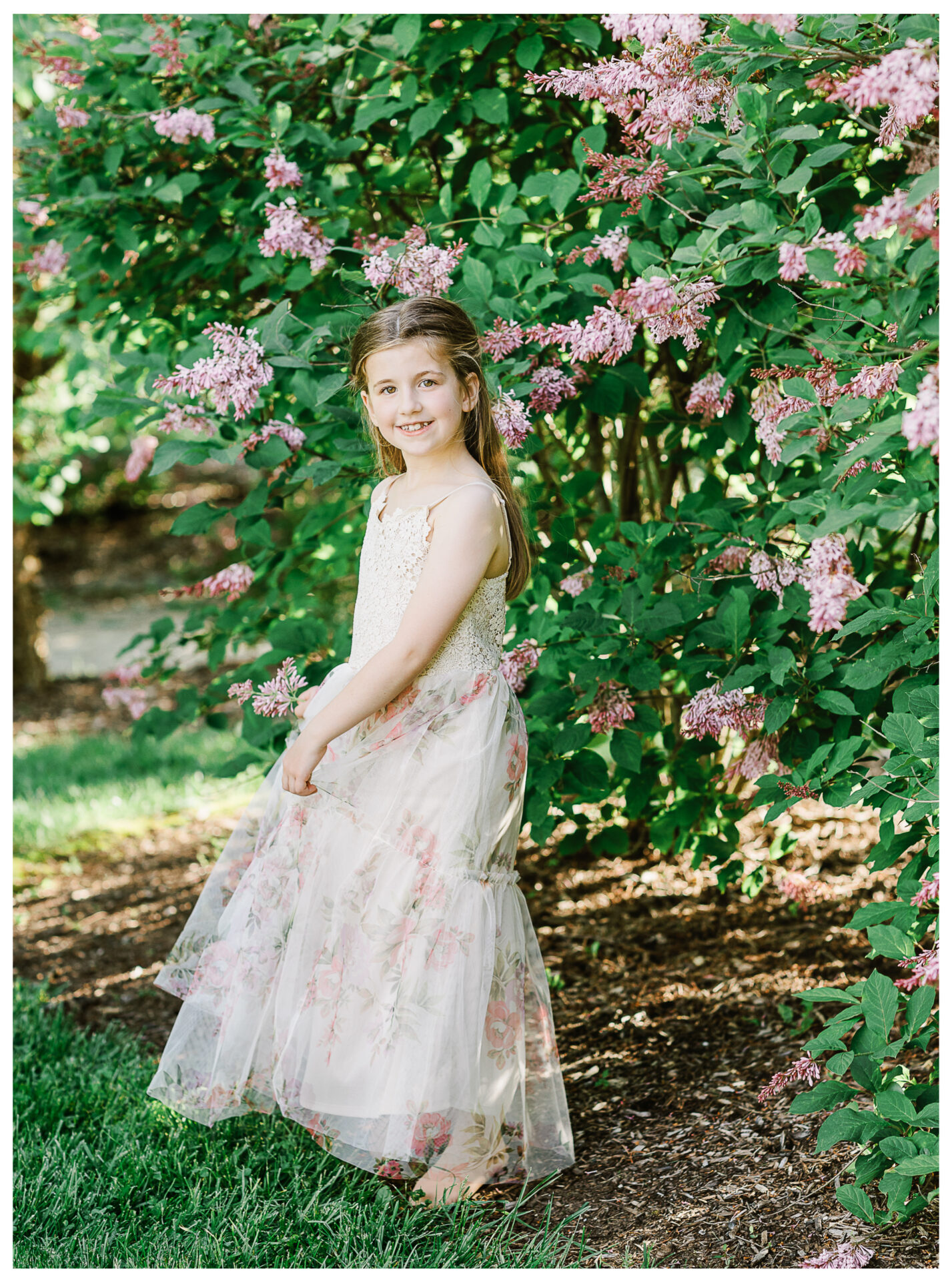 The oldest daughter smiling beside blossoming springtime flowers