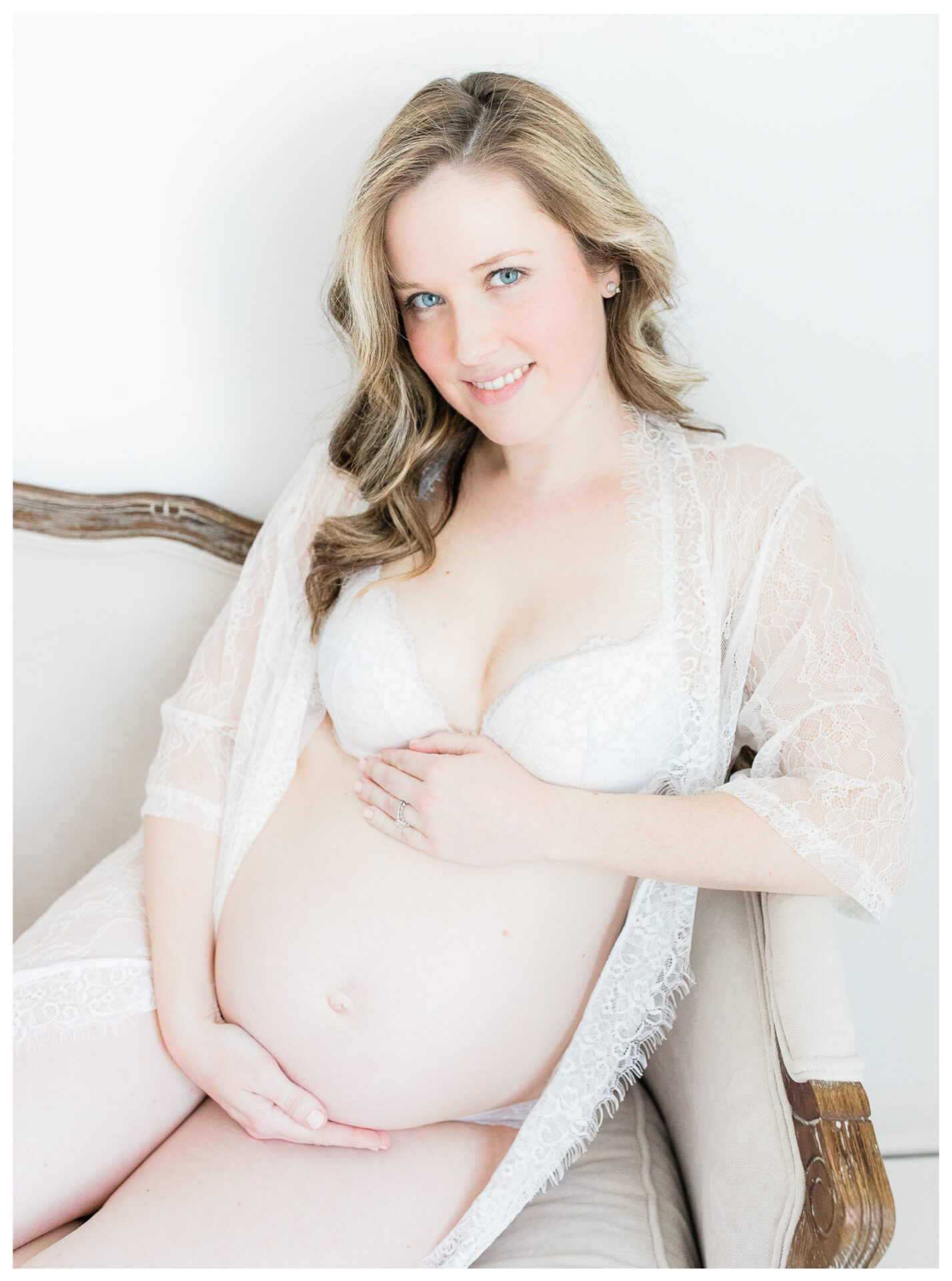 An expecting mother sitting on a vintage sofa holding her baby bump