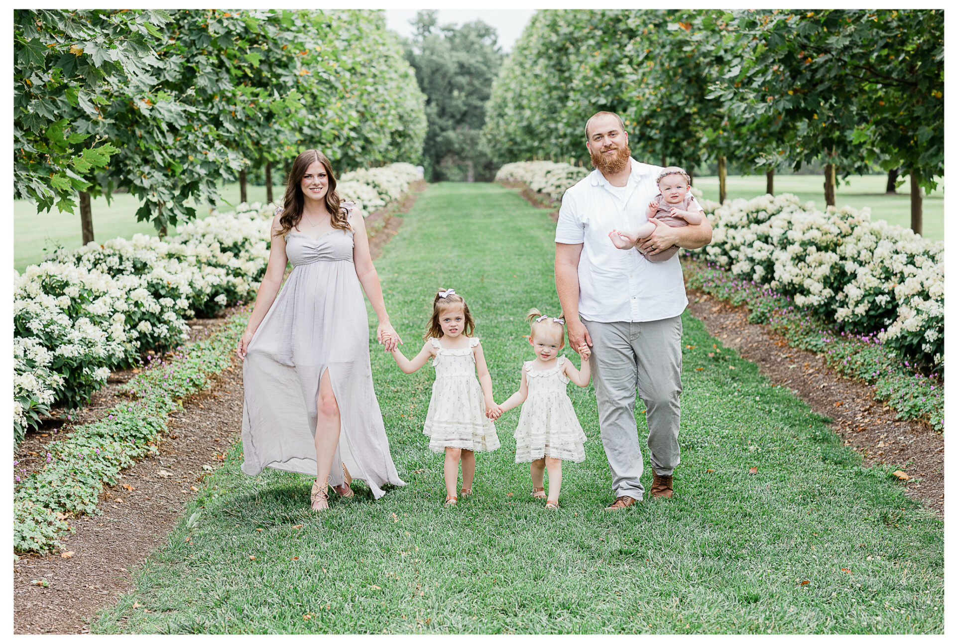 A young family of five walking together outside while smiling.