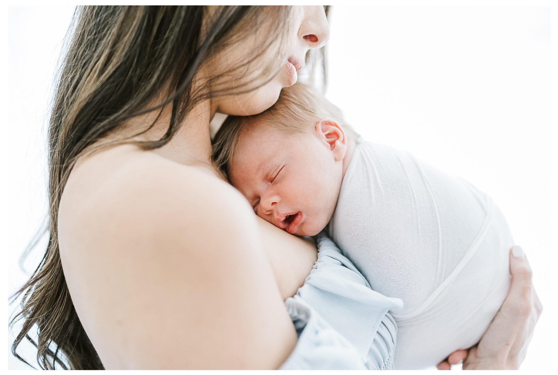 A close image of a newborn boy sleeping in his mother's arms.