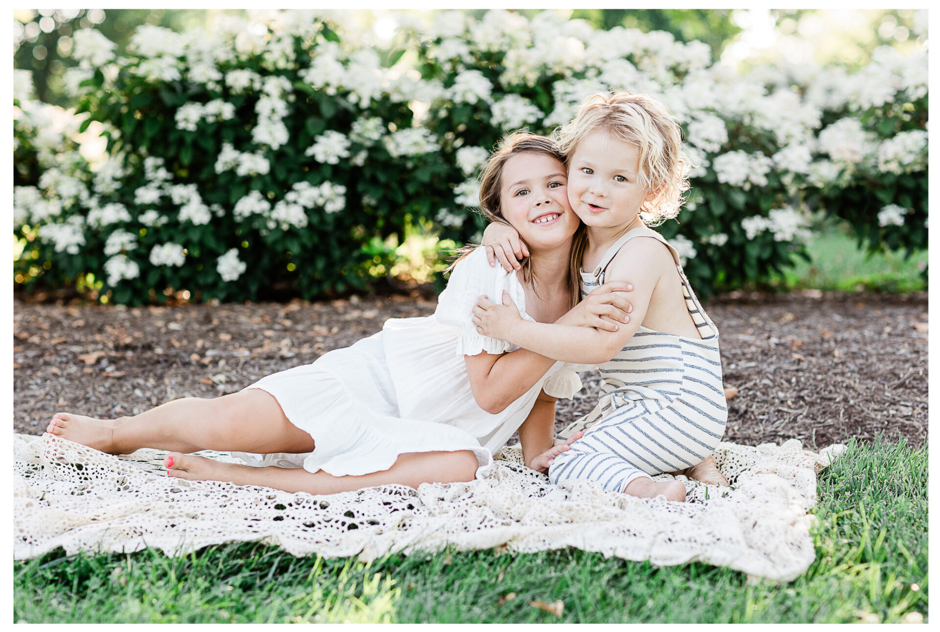 A young sister and her little brother wrapping their arms around each other while smiling. Dayton Ohio whimsical outdoor sibling session | Winter Freire Photography