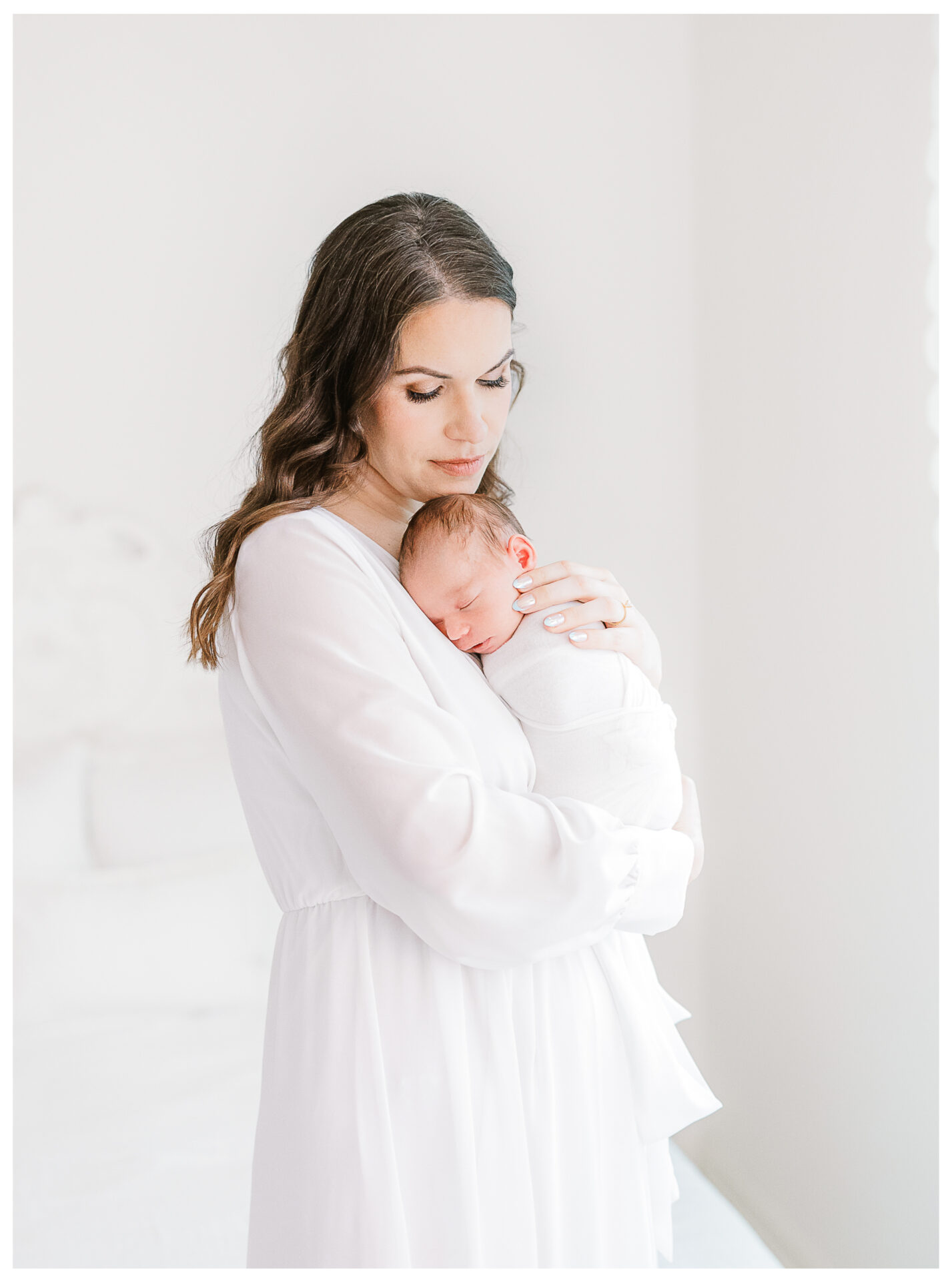 A mother snuggling her newborn son with her eyes closed.