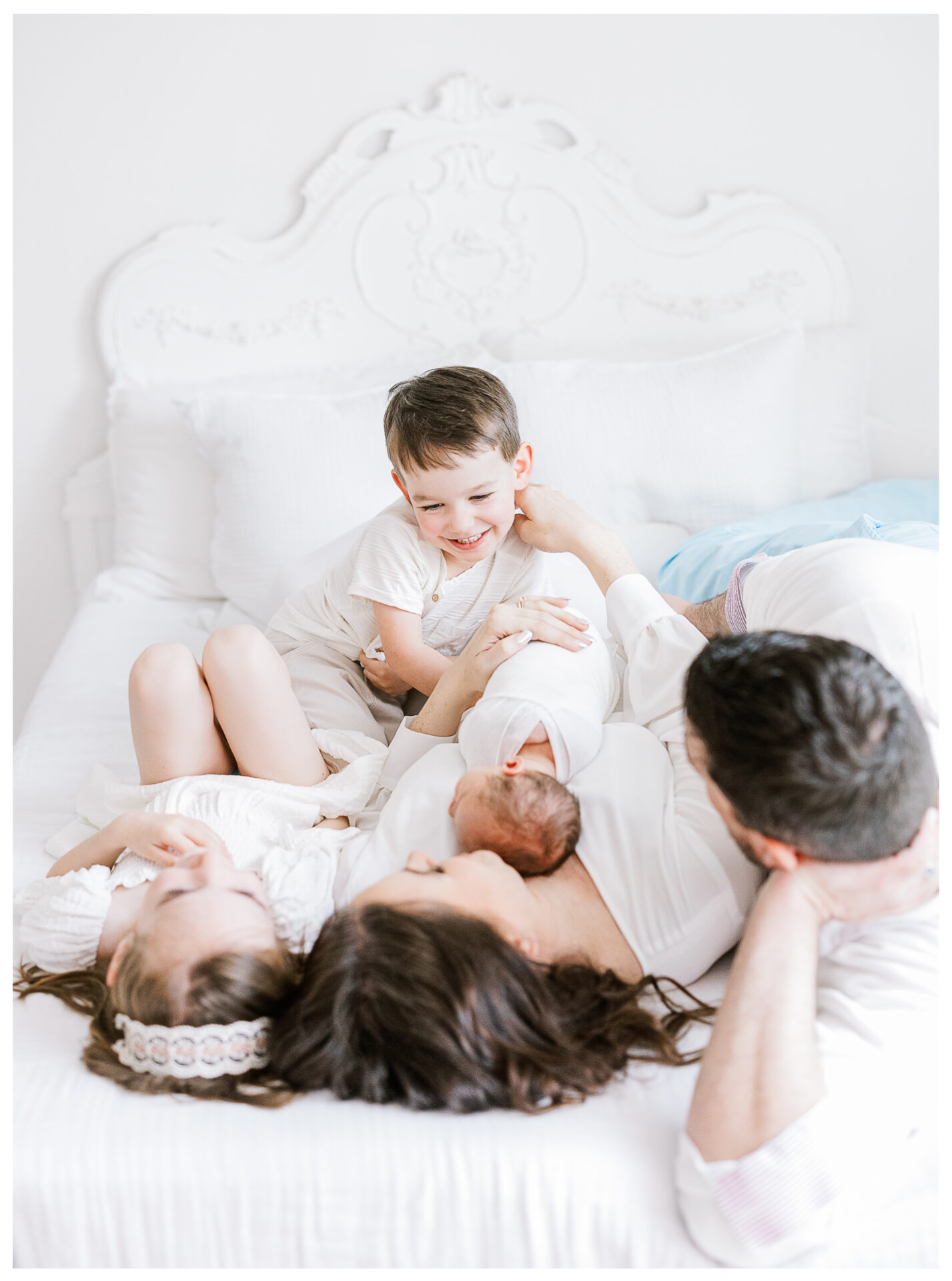 A young son smiles as his family snuggles together on a bed.
